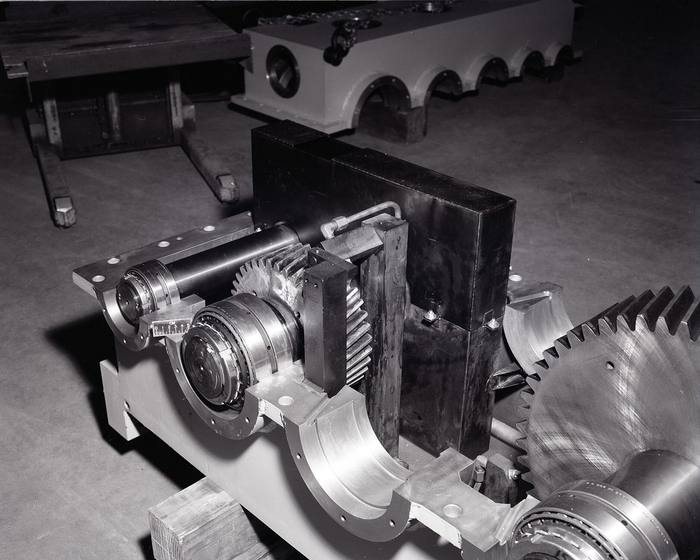 Cutaway industrial gearbox with gears and bearings on a shop floor