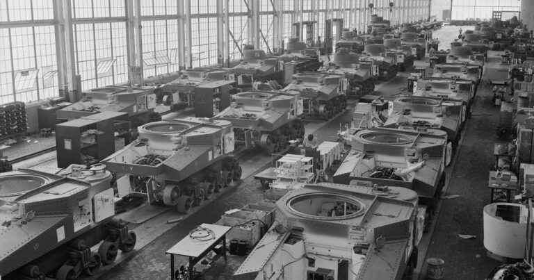 Rows of partially completed M3 tanks on three assembly lines inside the Chrysler tank arsenal, with overhead cranes.